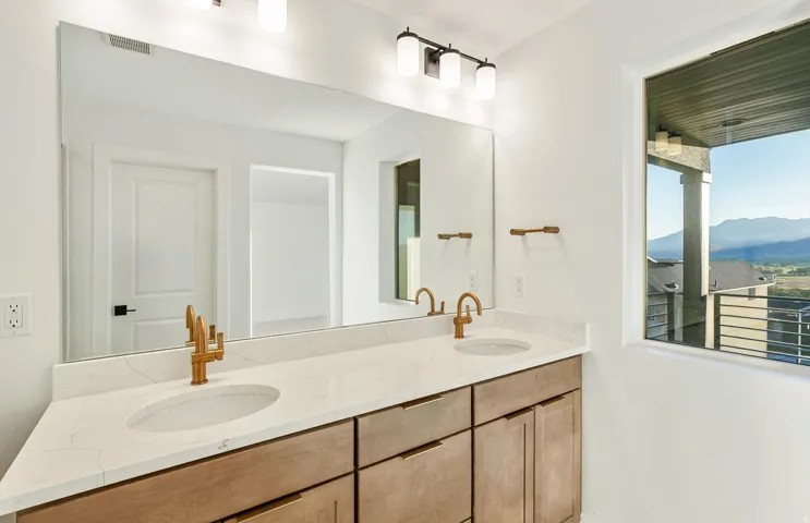 Double vanity featuring dual undermount sinks, bronze faucets, and a light-toned countertop