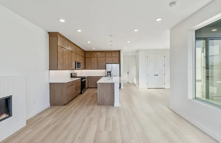 Open-concept living area featuring a kitchen with wood-finish cabinetry, stainless steel appliances, and a central island