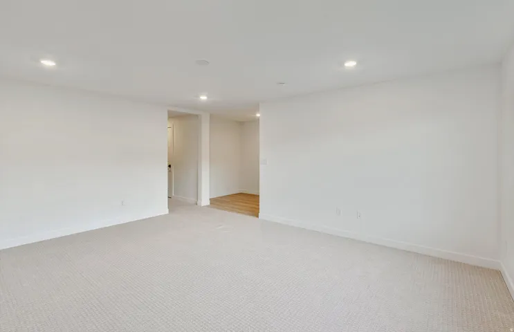 Spacious room with light-toned wall-to-wall carpeting and recessed lighting