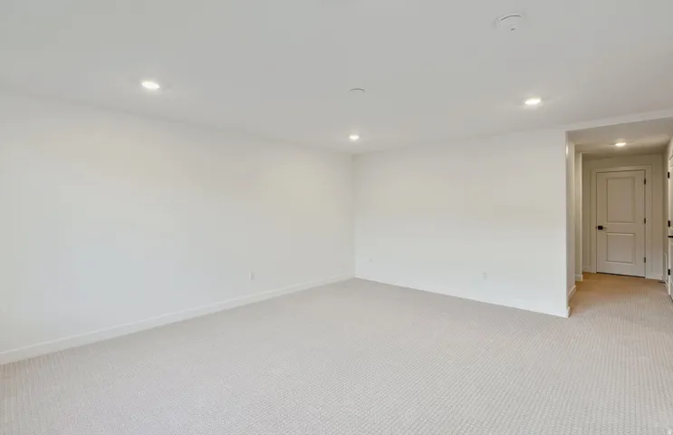Spacious interior room with light-toned carpet flooring and recessed ceiling lighting