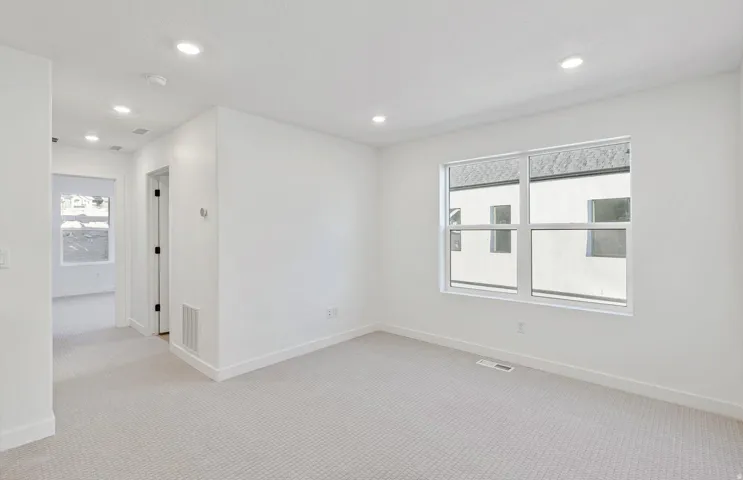 Bright room featuring a large window, recessed lighting, neutral carpeting, white walls, and white trim