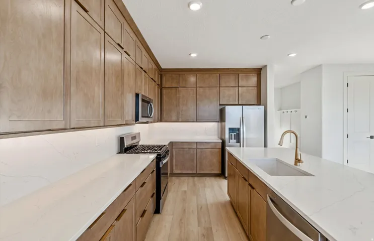 Kitchen featuring extensive wood-finish cabinetry, white countertops, and stainless steel appliances