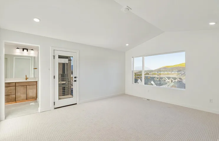 Spacious room featuring vaulted ceilings, recessed lighting, and a large window offering panoramic outdoor scenery