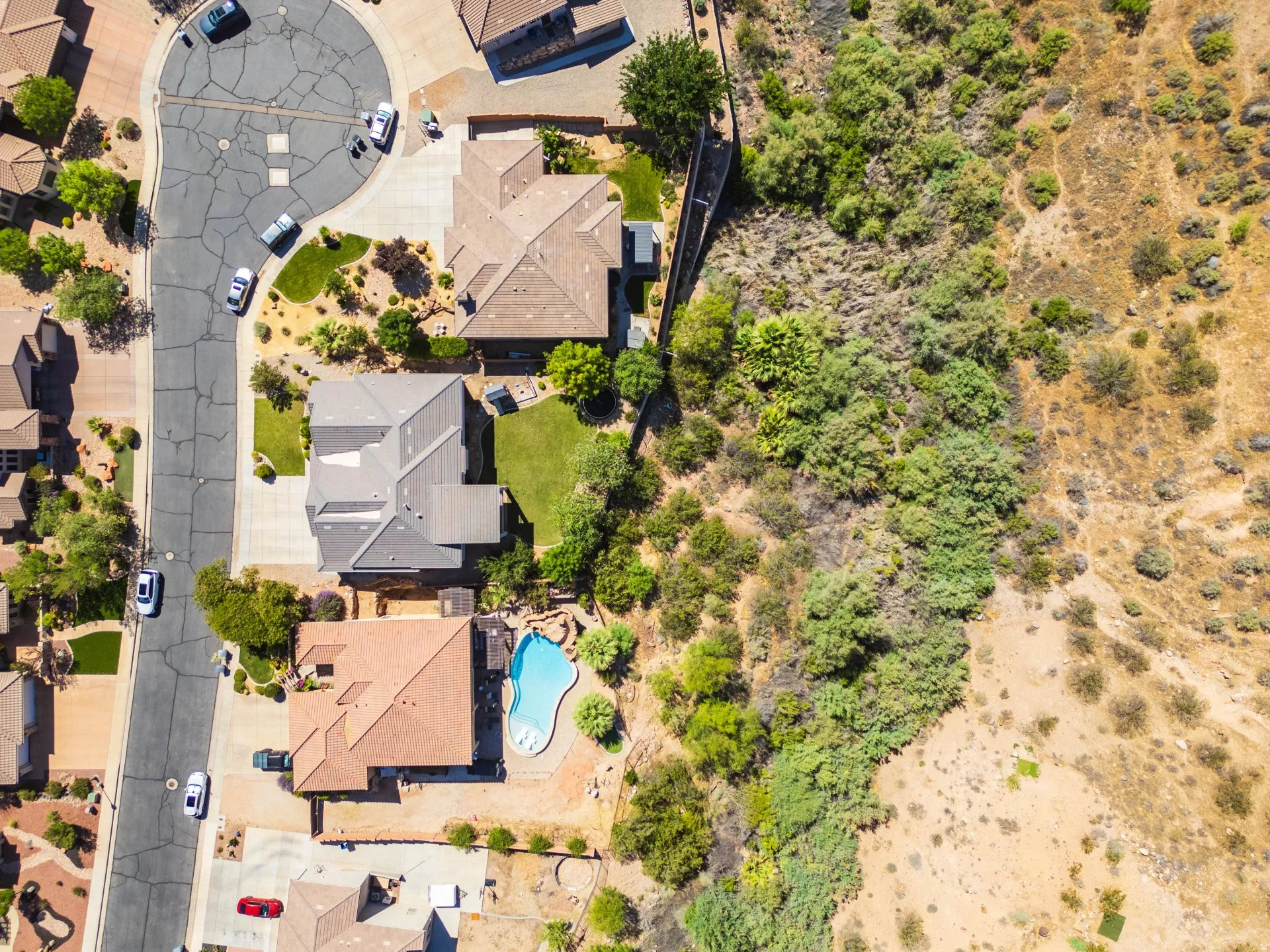 Residential property featuring a cul-de-sac street, mature landscaping, a private swimming pool, and proximity to natural desert terrain