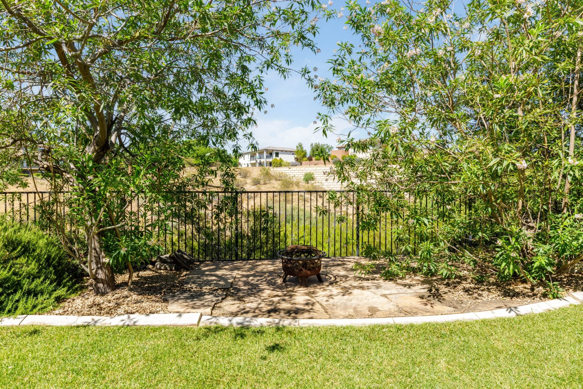 Expansive backyard featuring a manicured lawn, stone patio, and mature trees