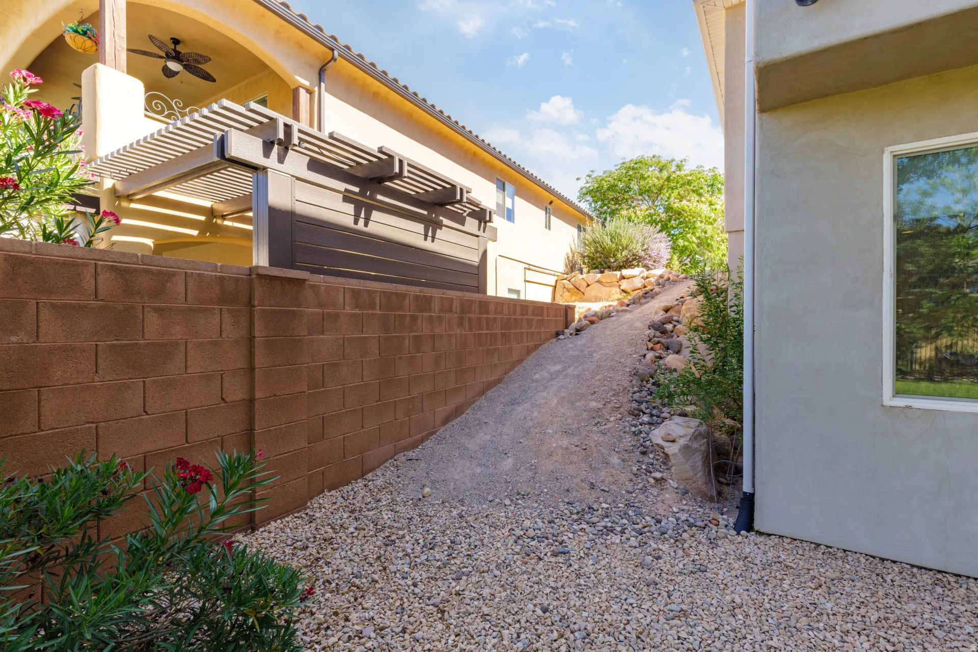 Terraced landscaping featuring a gravel pathway, a block retaining wall, and verdant plant beds