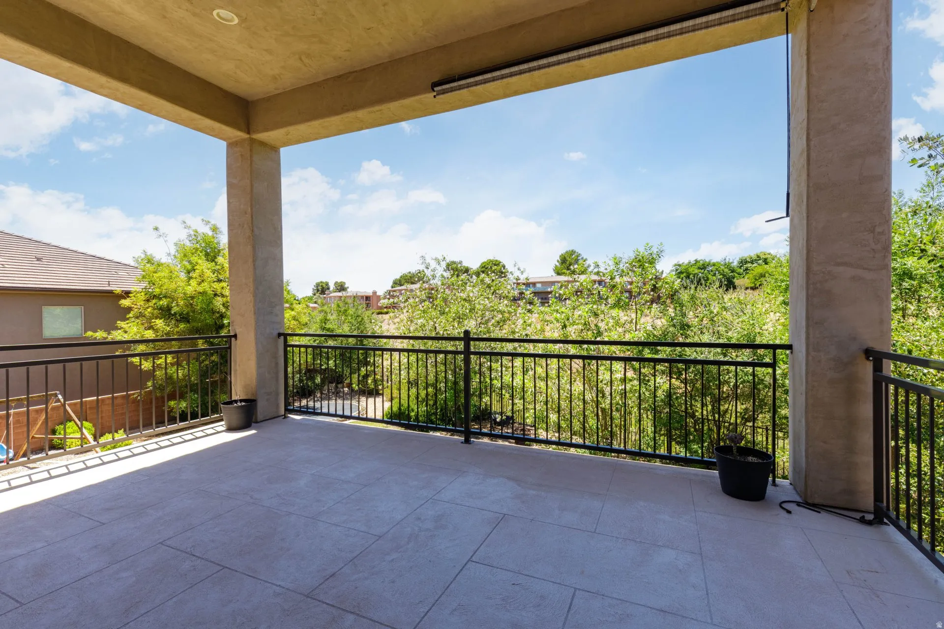 Expansive covered balcony featuring large format tile flooring and a black metal railing