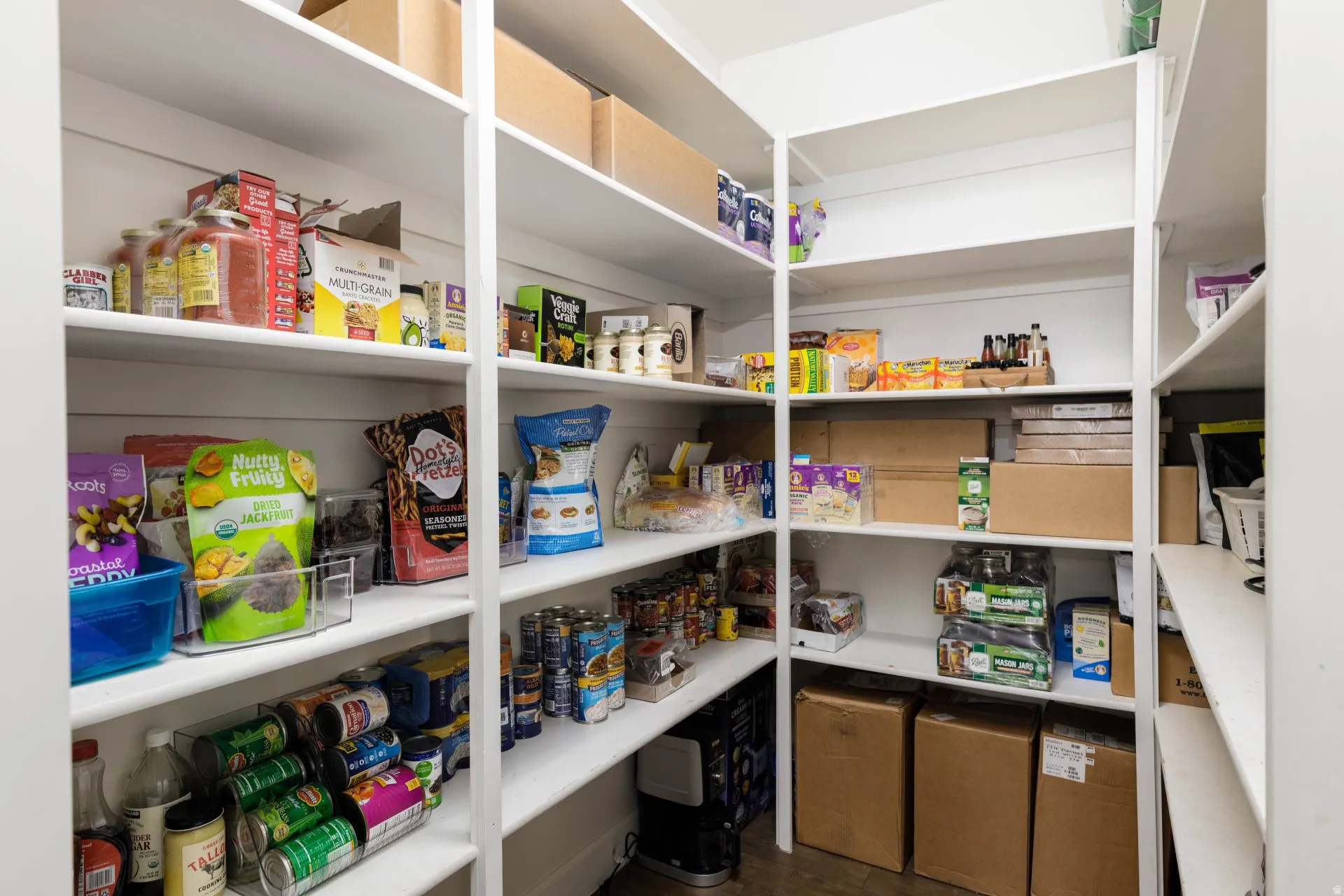 Spacious pantry featuring extensive built-in shelving, white shiplap-style wall accents, and durable flooring