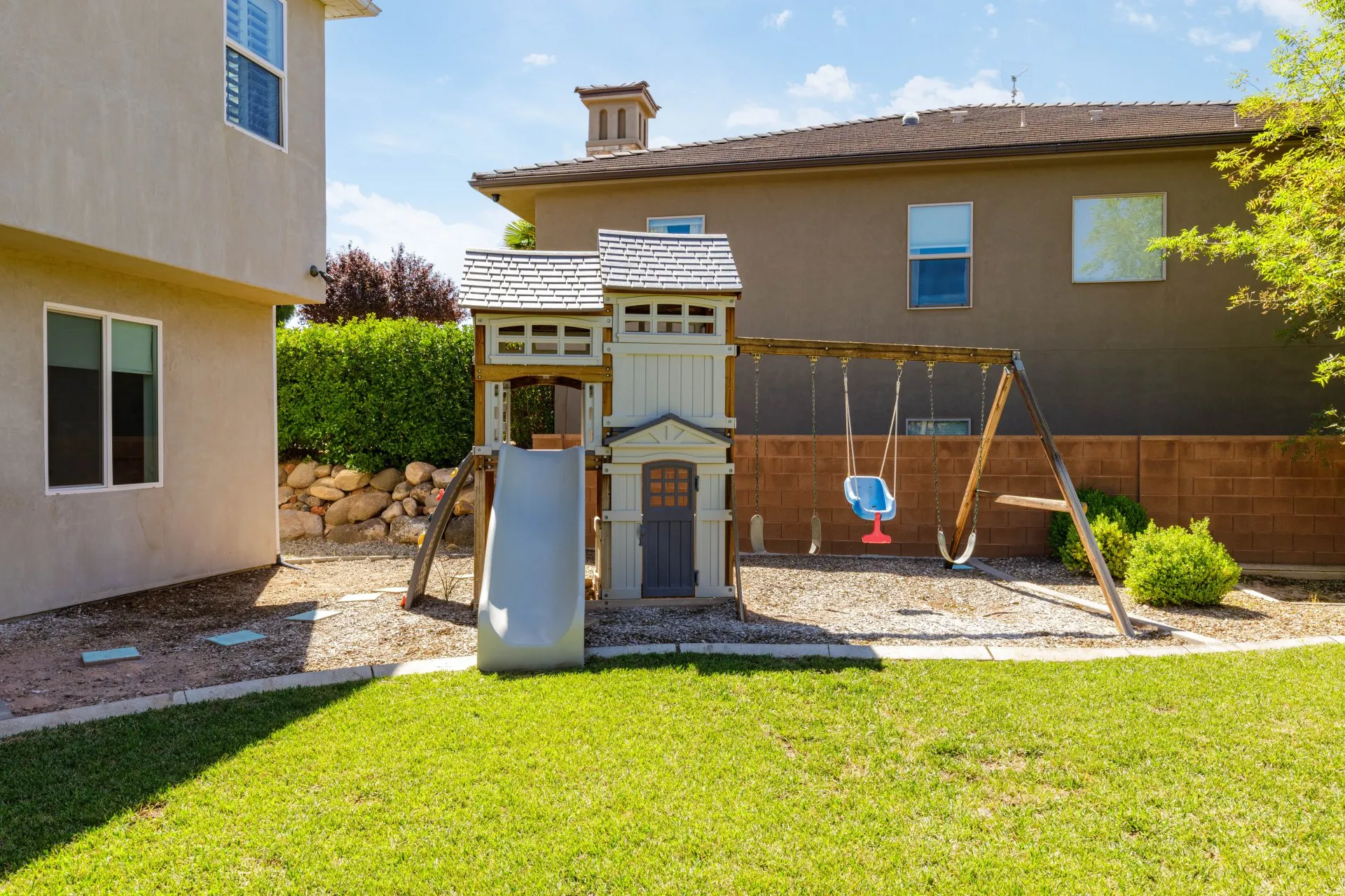 Expansive backyard featuring a lush lawn, concrete block fencing, and mature hedging