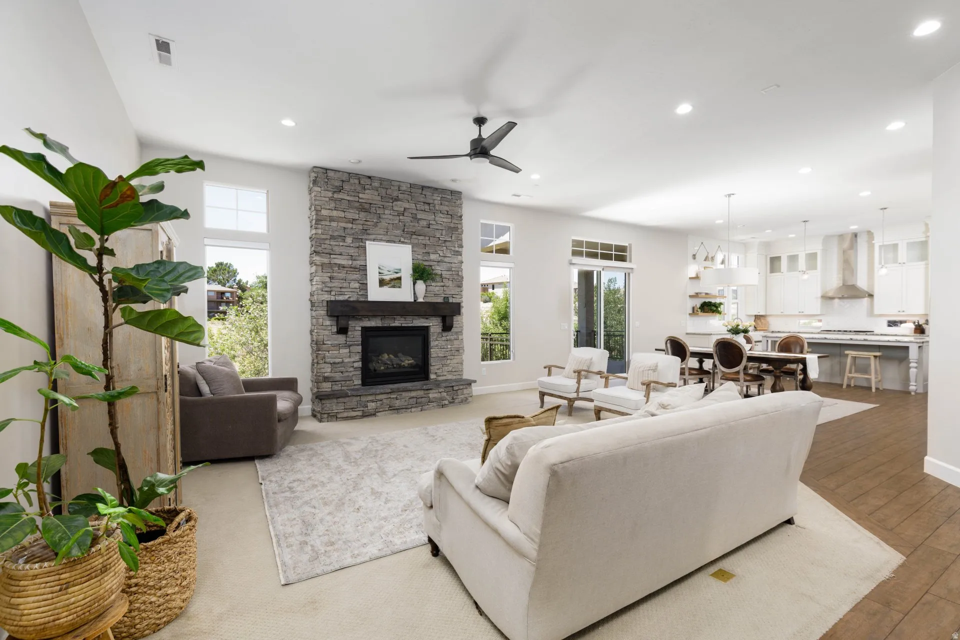 Expansive living area featuring a stone fireplace with a wood mantel, high ceilings, recessed lighting, and large windows