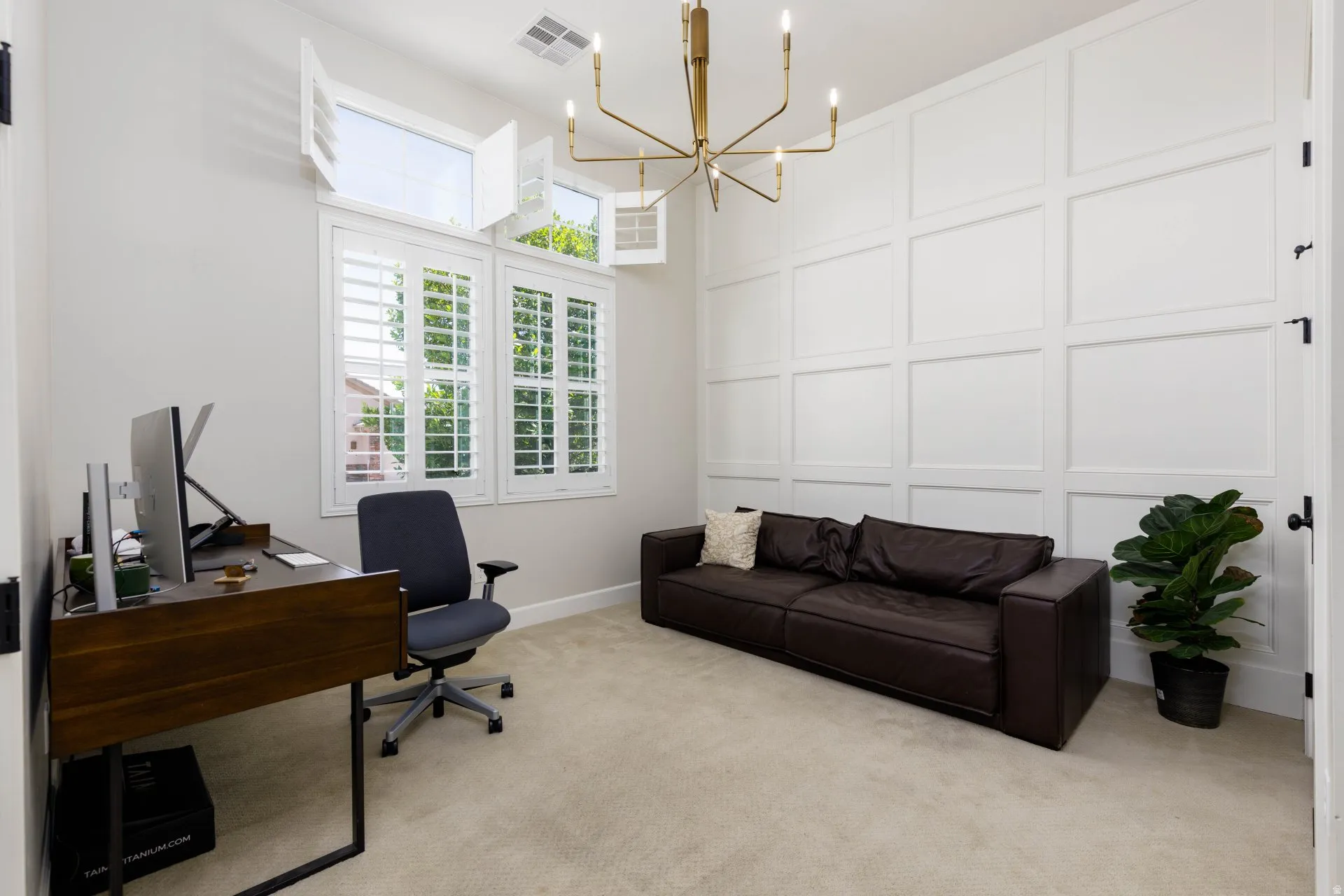 Panel accent wall featuring a modern chandelier and high ceilings
