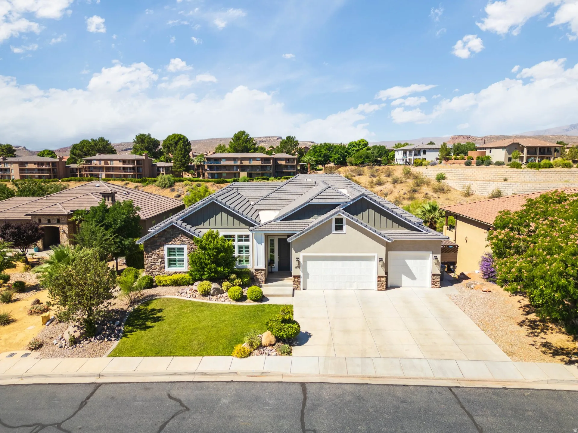 Contemporary residence featuring a two-car garage, stone and stucco exterior, and a tiled roof