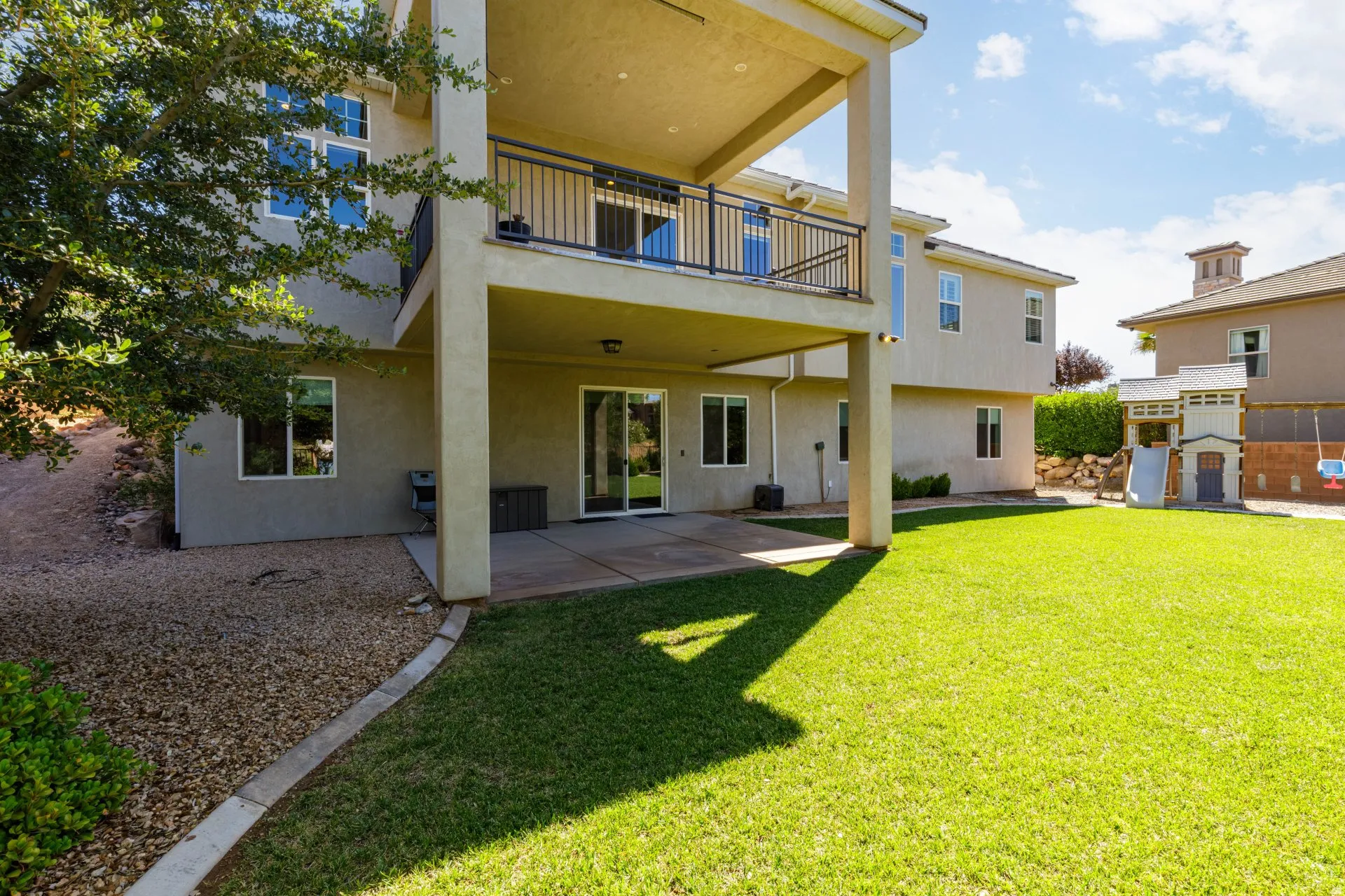 Expansive rear yard featuring a manicured lawn, concrete patio, and gravel landscaping