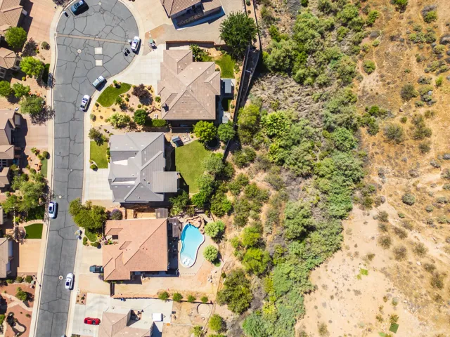Residential property featuring a cul-de-sac street, mature landscaping, a private swimming pool, and proximity to natural desert terrain