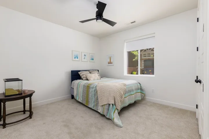 Carpeted room featuring a ceiling fan with black blades, a single window with a roller shade, white walls, and white trim