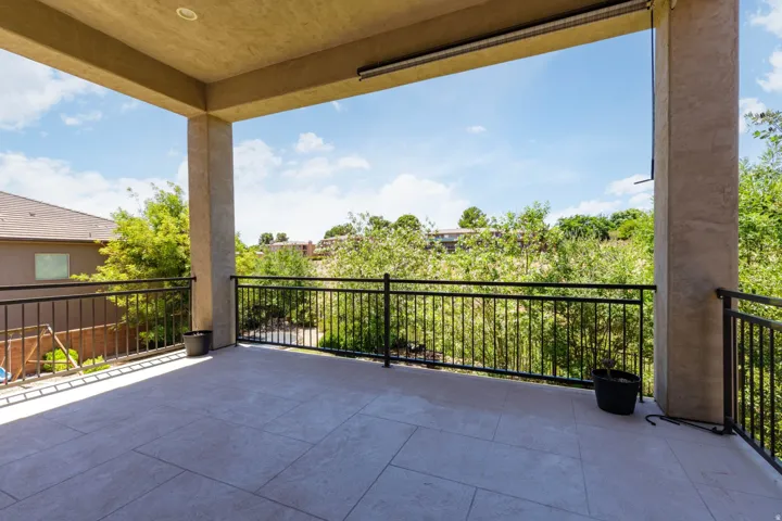 Expansive covered balcony featuring large format tile flooring and a black metal railing