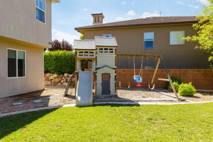 Expansive backyard featuring a lush lawn, concrete block fencing, and mature hedging