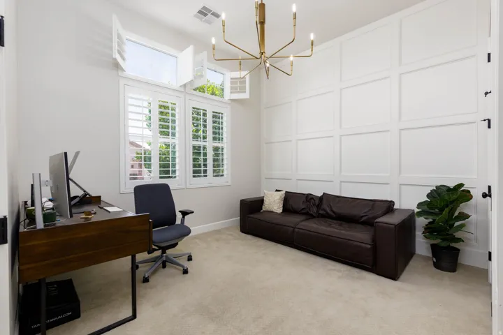 Panel accent wall featuring a modern chandelier and high ceilings