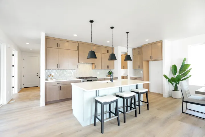 Kitchen featuring light wood-finish flooring, a central island with integrated seating, pendant lighting, and light wood cabinetry with modern hardware