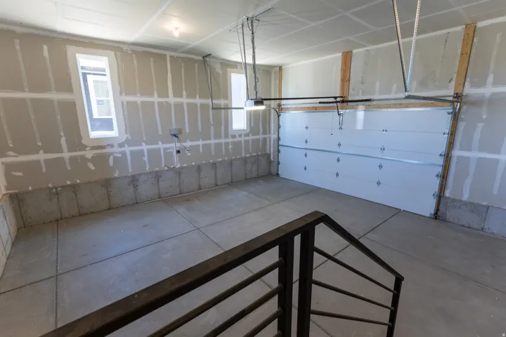 Spacious garage featuring a concrete floor, an overhead garage door, built-in windows, and a metal handrail at the entry point