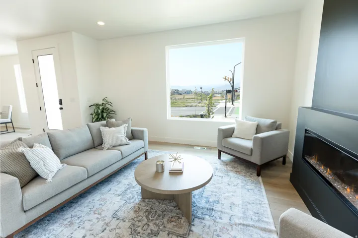 Spacious room with light wood-finish flooring, a contemporary built-in fireplace, and a large picture window offering exterior views
