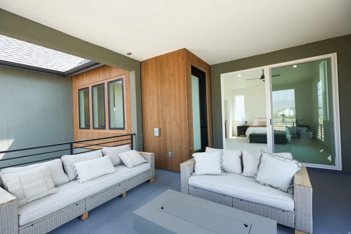 Private outdoor patio featuring a sliding glass door, wood-finish wall paneling, and a dark railing system