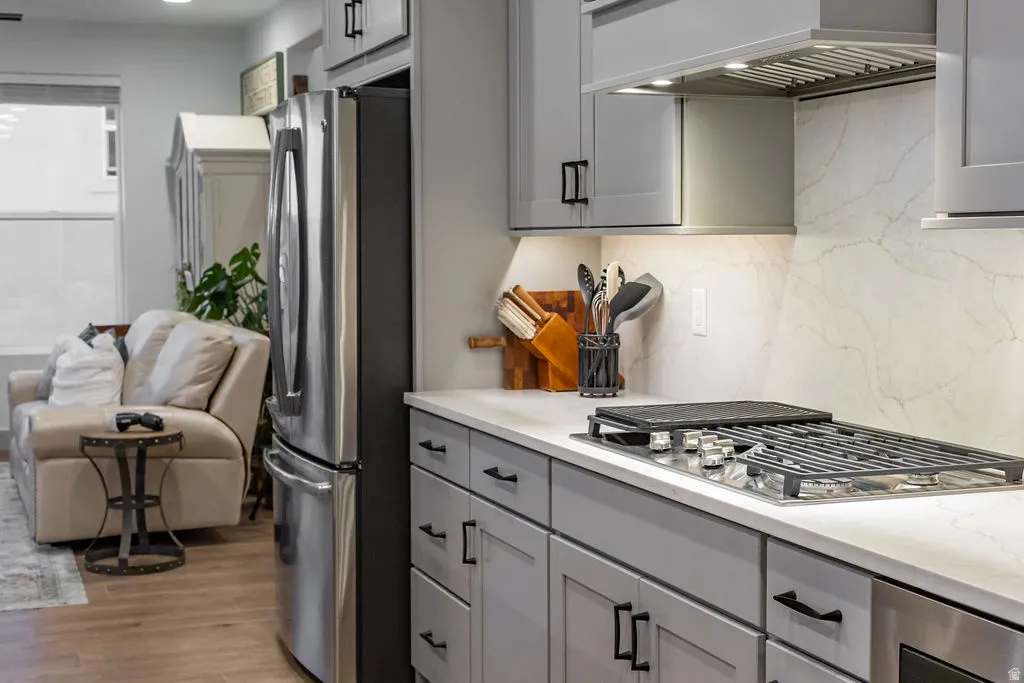 Kitchen featuring light gray cabinetry with black hardware, stainless steel refrigerator, and integrated gas cooktop with griddle