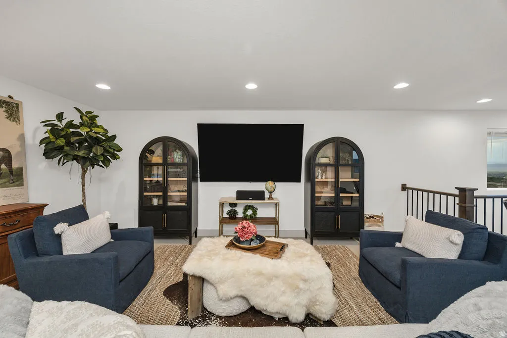 Bright living area featuring recessed lighting, a mounted wall screen, and white walls