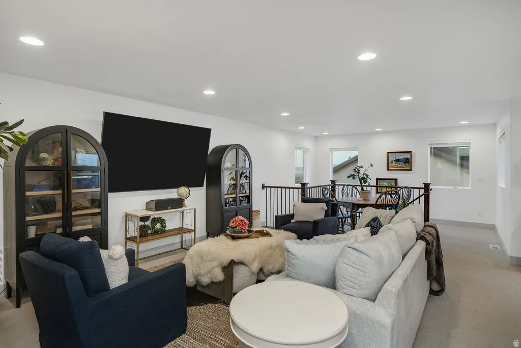 Spacious living area featuring recessed lighting, light-colored walls, and a railing overlooking a dining area