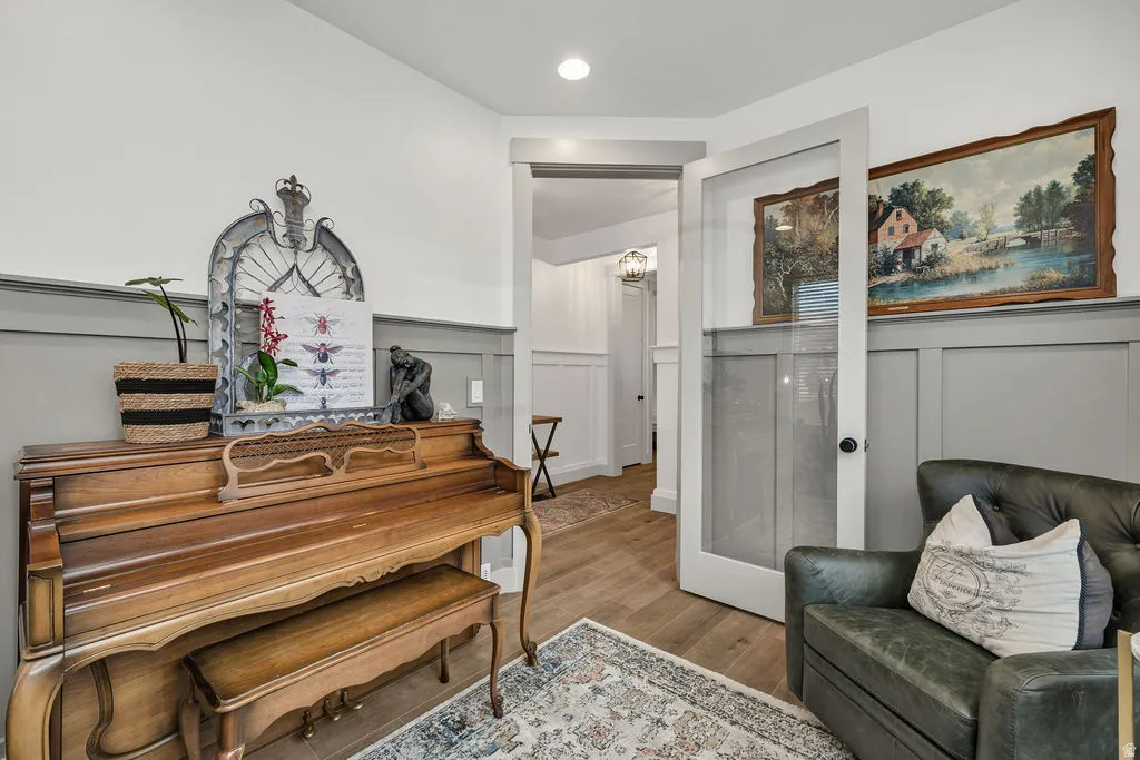 Light gray wainscoting and crown molding accent an interior space with wood-finish flooring
