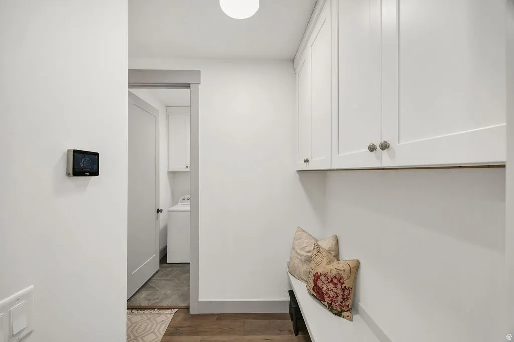 Entryway mudroom featuring white shaker-style cabinetry with satin nickel hardware, a built-in bench, and wood-finish flooring
