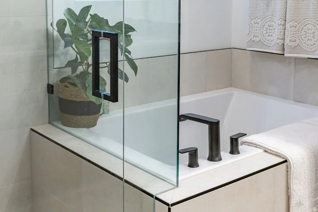 Soaking tub with a matte black deck-mounted faucet and separate controls