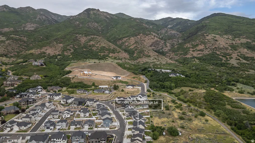 Aerial perspective showcasing a developed residential community bordered by natural mountainous terrain and a body of water