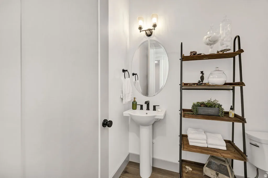 Pedestal sink with black faucet, an oval mirror, and a two-light vanity fixture