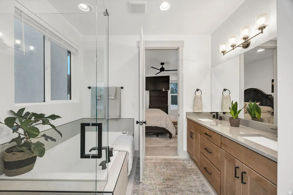 Bathroom featuring a double vanity with light wood cabinetry, white sinks, and a light-toned countertop