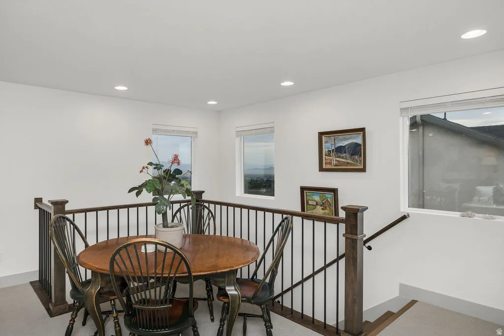 Open loft area featuring a wood-finish railing with black metal spindles and multiple windows
