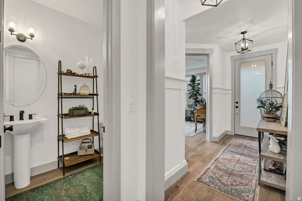 Hallway featuring wood-finish flooring, wainscoting, and a panel door with frosted glass