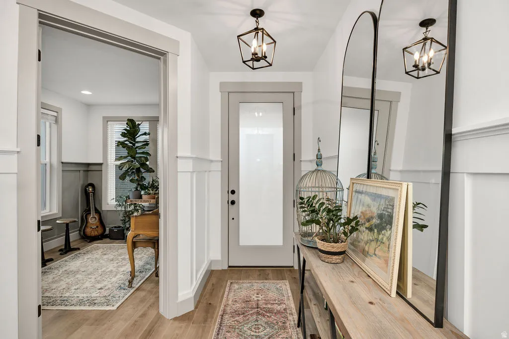 Foyer featuring wood-finish flooring, wainscoting, and a grey-framed entry door with frosted glass