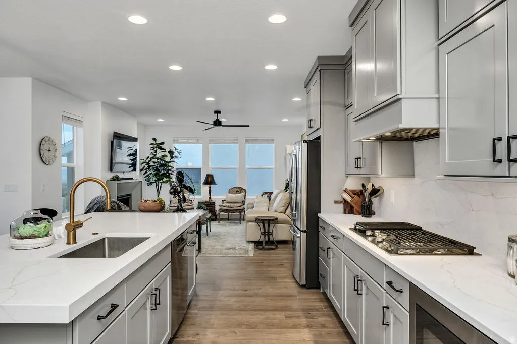 Modern kitchen featuring light gray cabinetry, white countertops, and a gold-finish faucet