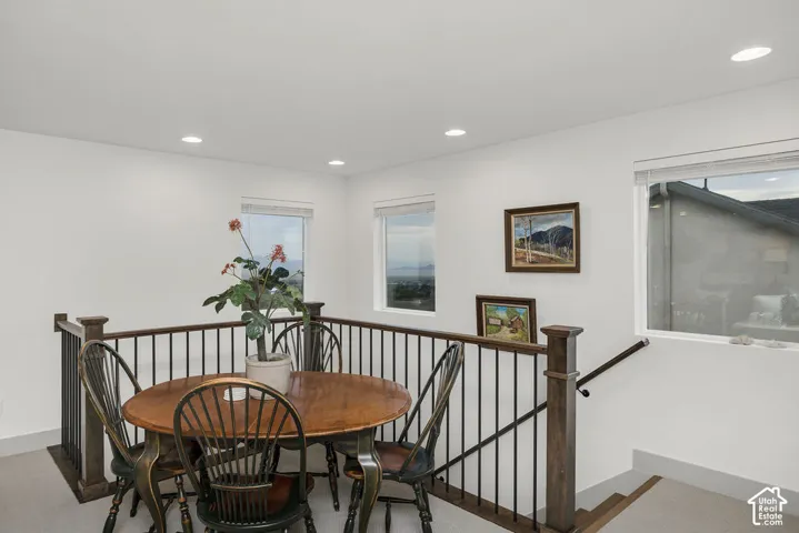 Open loft area featuring a wood-finish railing with black metal spindles and multiple windows