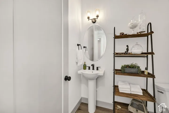 Pedestal sink with black faucet, an oval mirror, and a two-light vanity fixture