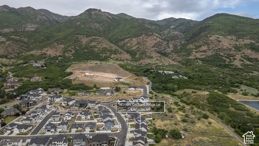 Aerial perspective showcasing a developed residential community bordered by natural mountainous terrain and a body of water