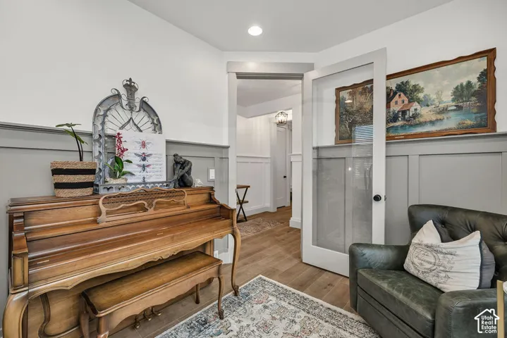Light gray wainscoting and crown molding accent an interior space with wood-finish flooring