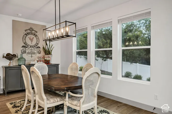 Dining area featuring wood-finish flooring, a linear chandelier, and a built-in sideboard