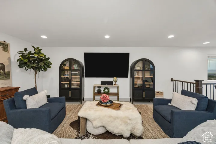 Bright living area featuring recessed lighting, a mounted wall screen, and white walls