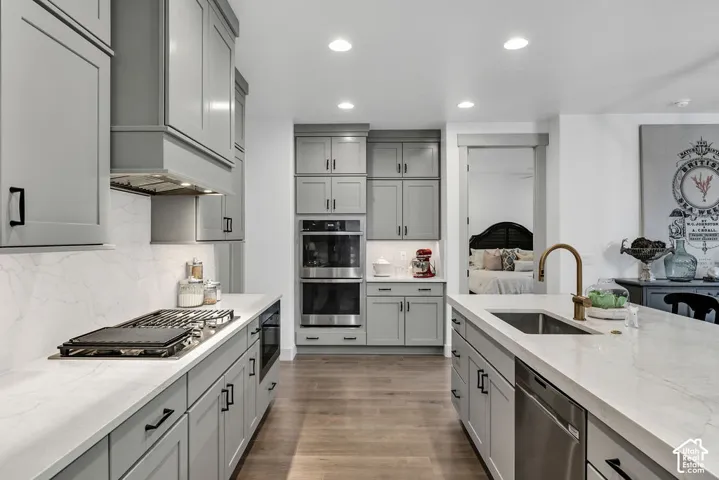 Kitchen featuring light gray cabinetry, light-toned countertops, wood-finish flooring, recessed lighting, and stainless steel appliances