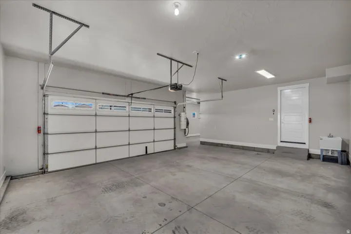 Spacious garage featuring a sectional overhead door with window panels, concrete flooring, recessed lighting, and an additional service door