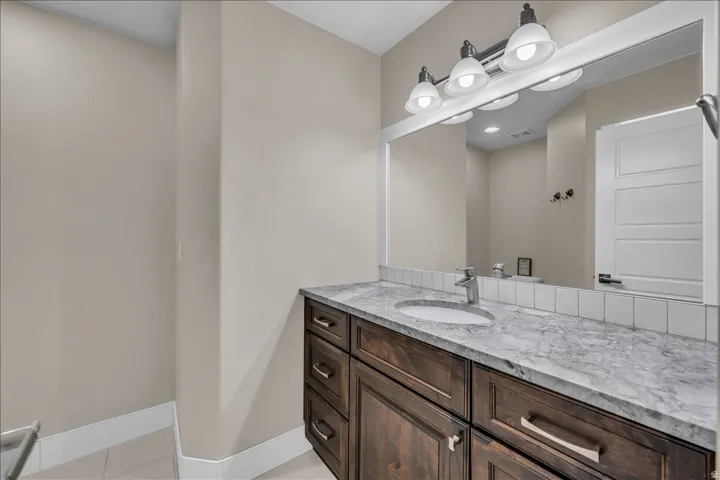 Vanity featuring a polished countertop with an integrated sink, a single-handle faucet, and dark wood-finish cabinetry