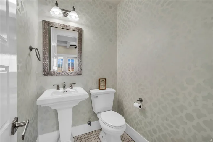 Pedestal sink with a polished chrome faucet, framed mirror, and coordinating wall-mounted light fixture