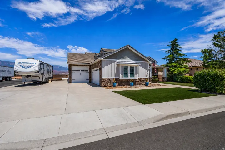 Contemporary ranch-style residence featuring a prominent two-car garage, stone veneer accents, and a bay window with shutters